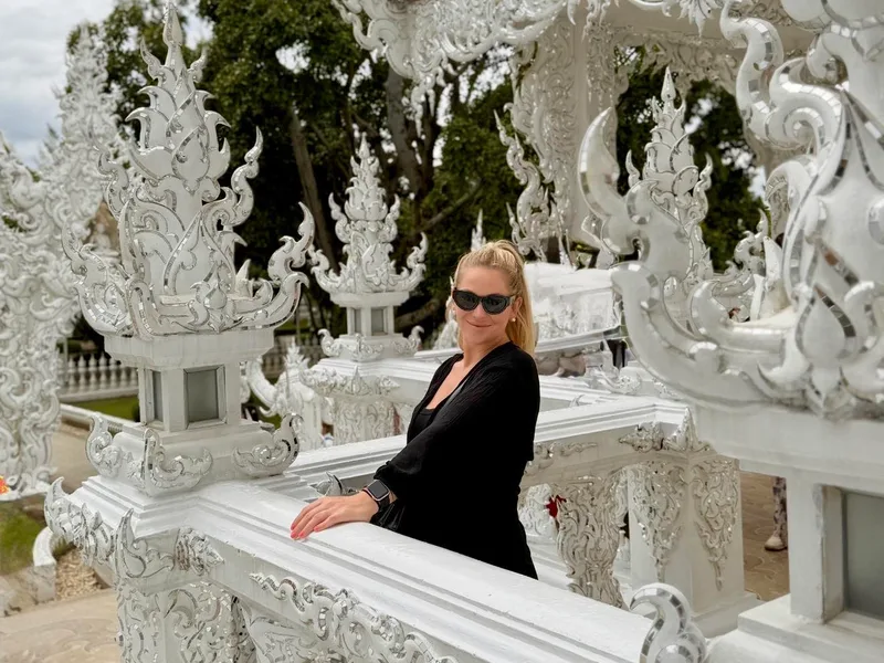 Nikol v černých šatech mezi bílými ornamenty Bílého chrámu v Chiang Rai